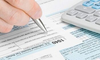 close up of a hand holding a pen filling out a form 1040